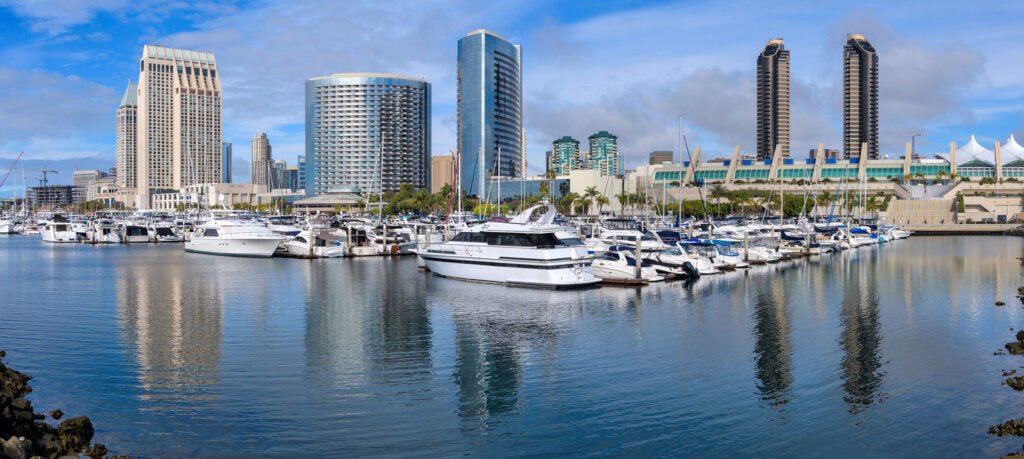On a tranquil winter day, the San Diego Marina gleams under the sun's warmth, with the iconic downtown skyline of San Diego, California, USA, standing tall against the clear blue sky.