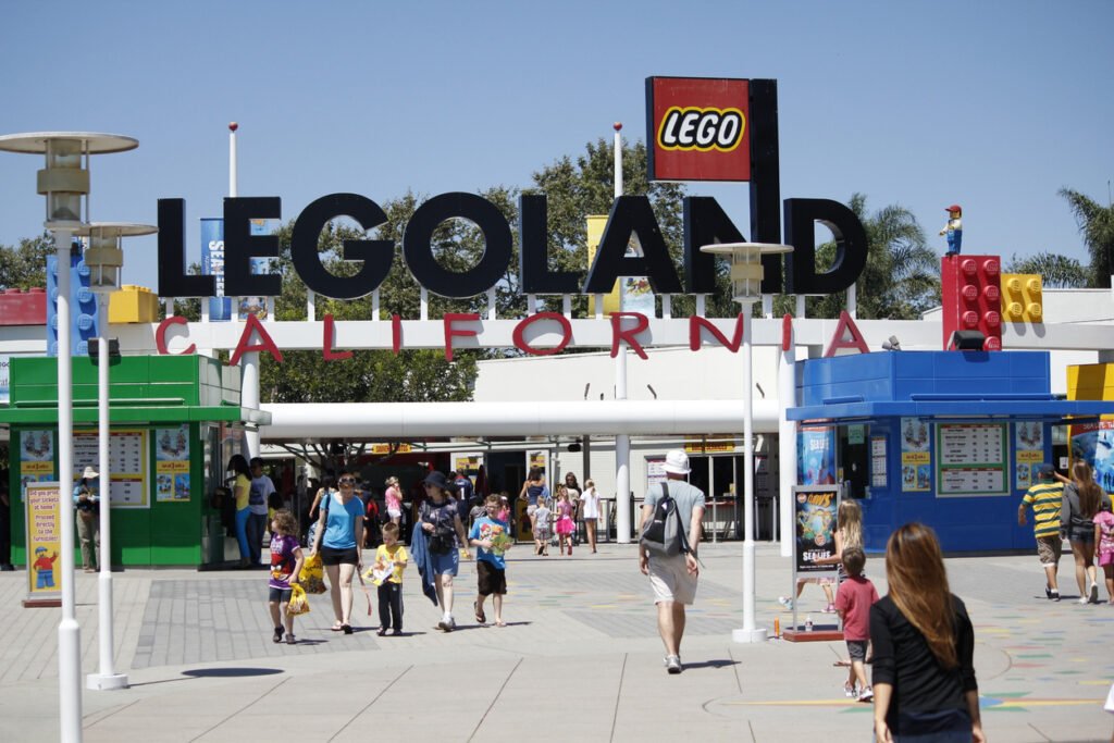Crowds of visitors eagerly enter and exit the gates of Legoland California, a vibrant theme park brimming with creativity and excitement for all ages.