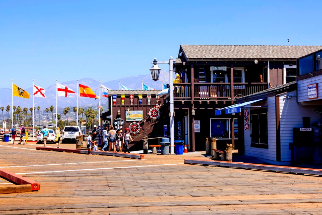 People enjoy the picturesque scenery while strolling along Stearns Wharf, immersing themselves in the coastal charm and vibrant atmosphere of this iconic Californian landmark.