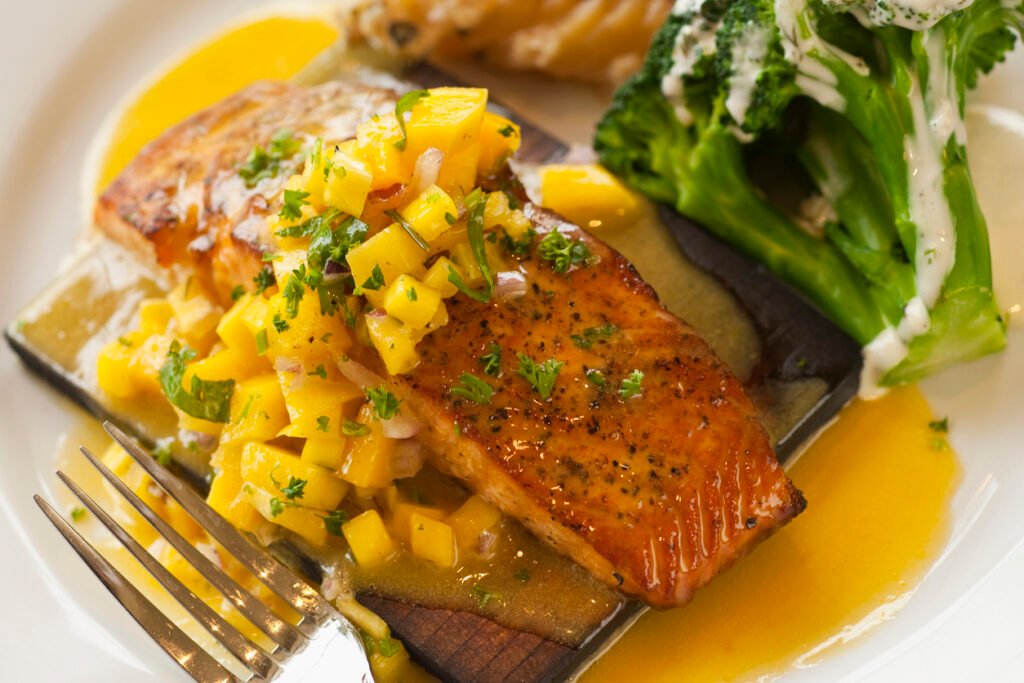 Savor the exquisite flavors of cedar plank-cooked salmon topped with zesty mango salsa, a culinary delight synonymous with the coastal elegance of Santa Barbara, California, USA.