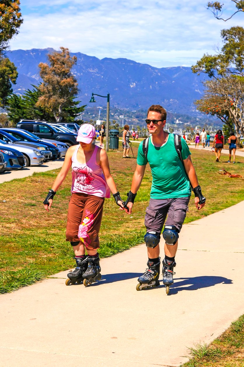 In Santa Barbara, CA, USA, couples glide gracefully on rollerblades along the scenic coastal path, framed by swaying palms and the shimmering Pacific Ocean.